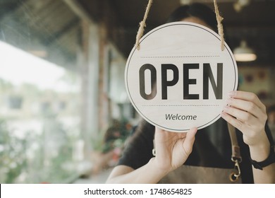 Welcome. Open. barista, waitress woman turning open sign board on glass door in modern cafe coffee shop ready to service, cafe restaurant, retail store, small business owner, food and drink concept - Powered by Shutterstock