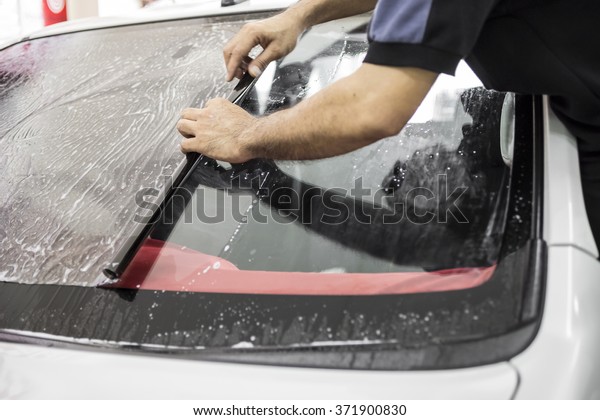 Welcome to our car service station. Closeup image
of a car mechanic man attaching tinting film foil to car window in
specialized service
station