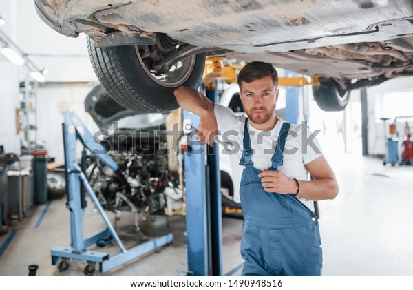 Welcome to our garage. Employee in the\
blue colored uniform works in the automobile\
salon.