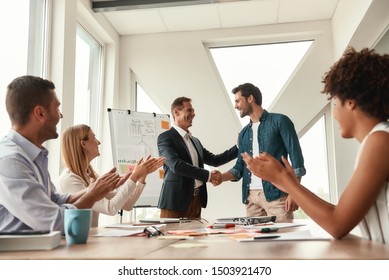 Welcome to our team Two cheerful colleagues shaking hands and smiling while having a meeting in the modern office - Shutterstock ID 1503921470