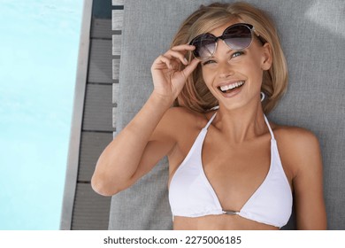 Welcome to paradise. an attractive blonde woman lying by a pool. - Powered by Shutterstock