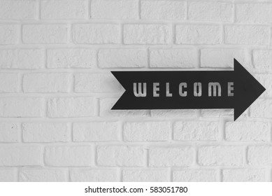 Welcome with right direction signboard on white brick wall background