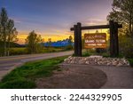 Welcome sign at the entrance to Grand Teton National Park in Wyoming, with Teton Mountain Range in the background. Photographed at sunset.