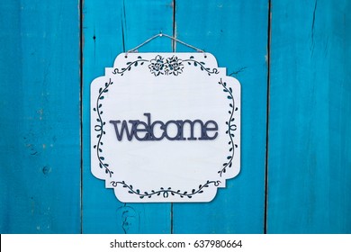 Welcome Sign With Floral Border Hanging On Antique Rustic Teal Blue Wood Door; Family, Home, Love Concept Background With Painted Copy Space