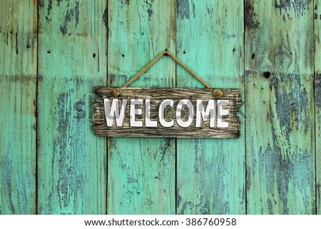 Welcome sign hanging on antique rustic mint green wood background
