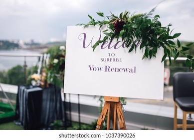 Welcome Sign On Easel With White Frame Stands On The Roof Top During Wedding Party. Reception. Vow Renewal