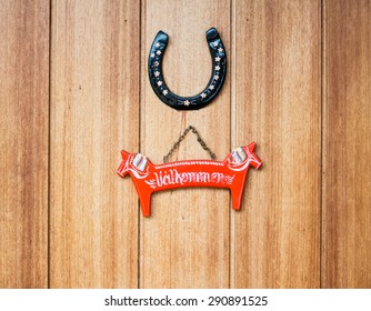 Welcome Sign In A Shape Of Dalahast And Horseshoe On A Door In Dalarna County, Sweden