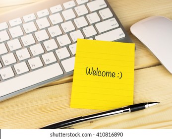 Welcome With Smily Face On Sticky Note On Work Table