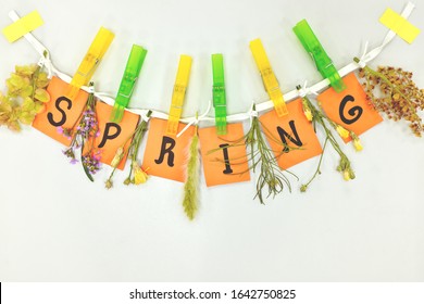 Welcome spring season hanging wall decoration in pastel orange color. Colored paper cards clipped on a string.