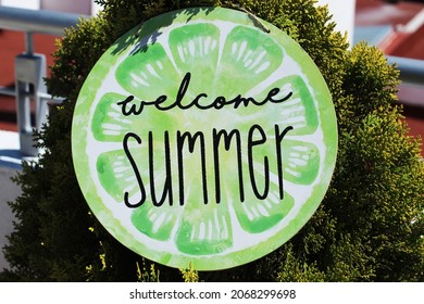 Welcome Summer Sign Hanging From A Small Little Tree. 