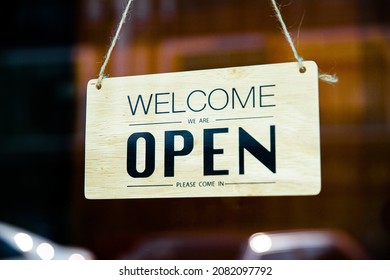 Welcome We Are Open Signage In The Front Door Of Shop And Restuarant After Covid-19 Lockdown On The Blurred Background.