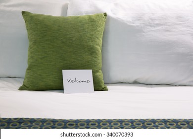 Welcoming Hotel Bed With Pillows And Welcome Card Close Up.