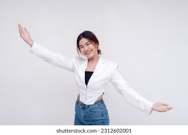 A welcoming young woman holding her arms wide open in greeting while looking at the camera. Isolated on a white background. - Shutterstock ID 2312602001