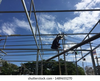 The Welder Climbs Onto The Beam To Weld The Steel Structure For The Roof. Risky And Unsafe Work Without Safety Equipment Causes An Accident