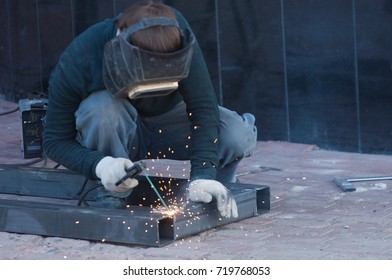 The welder cooks the frame. The welder cooks the metal. The welder cooks metal structures. Welding works. Sparks, molten metal