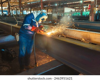 Welder is Gouging Back Weld adds Joint Steel H-Beam with Air Carbon Arc Gouging Machine and Dressed Properly with Personal Protective Equipment(PPE) for Safety, at The Industrial Factory. - Powered by Shutterstock