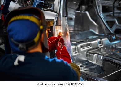 Welder In Helmet Works With Metal Parts Of Car Carcass