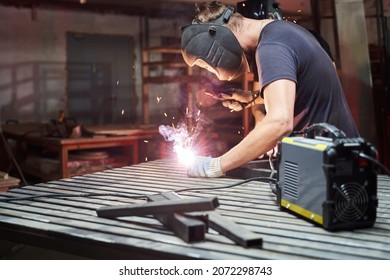 welder in a helmet works as a welding machine in a workshop.sparks from welding - Shutterstock ID 2072298743