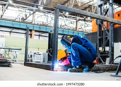 A welder at an industrial enterprise welds metal structures from an iron profile. Unrecognizable person. Copy space
