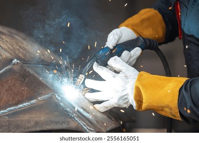 Welder is joining metal parts using a welding torch, creating a shower of sparks and smoke in a workshop - Powered by Shutterstock