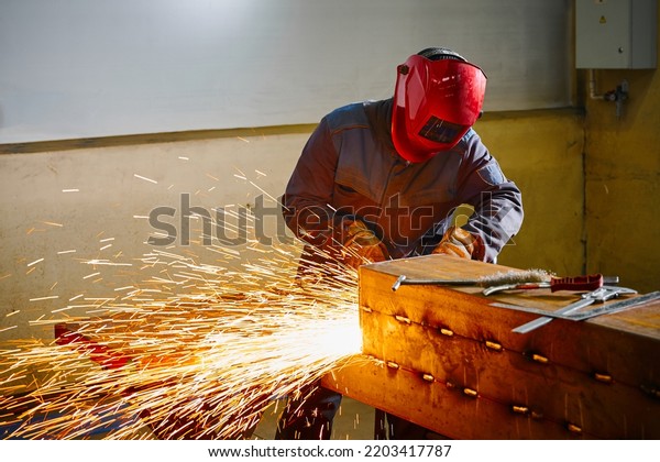 Welder in mask cuts steel beam with cutting blowpipe\
in shop