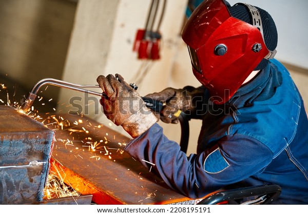 Welder in mask cuts steel beam with cutting blowpipe
in shop