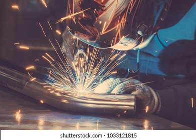 Welder in mask welding metal and sparks metal. Toned image. Welding with sparks close up view - Powered by Shutterstock