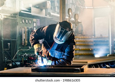 The welder performs welding task at his workplace in the factory, while the sparks "fly" around, he wears a protective helmet. - Powered by Shutterstock