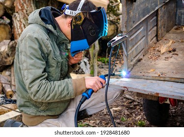 welder performs work at home with a semi-automatic welding machine in a protective mask without gloves.