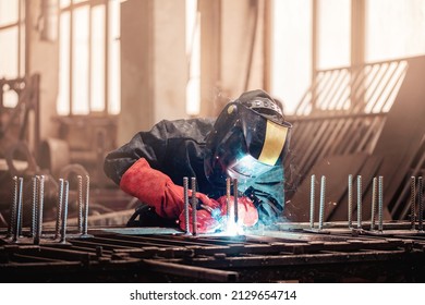 Welder in protective uniform with mask. Factory industrial worker on workplace with spark.