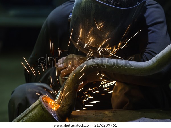Welder repairing a\
car exhaust pipe\
close-up