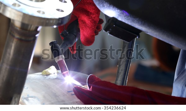 Welder\
stainless steel worker is welding a big valve\
body
