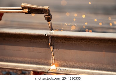 Welder using gas torch to cut metal beam, with sparks flying. Skilled craftsmanship and risks involved in industrial metal fabrication. Precision and danger of process. Cutting steel beam with a torch - Powered by Shutterstock