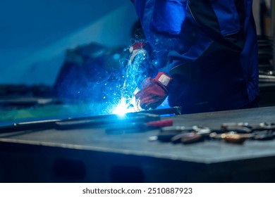 Welder using a torch, bright blue flame and sparks in a workshop, creating a strong weld on metal.