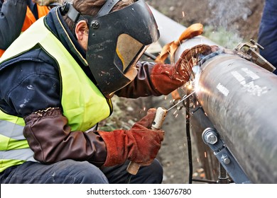 Welder wearing protective clothing for welding industrial construction oil and gas or water and sewerage plumbing pipeline outside on site