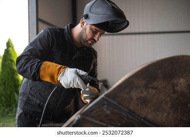 Welder wearing protective gear and using a welding torch to join metal parts in a workshop - Powered by Shutterstock