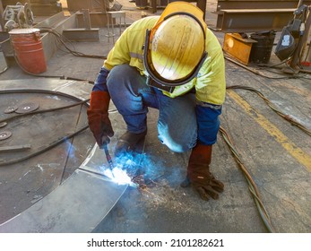 Welder is welding add joint steel plate for built-up ring with process Flux Cored Arc Welding(FCAW) and dressed properly with personal protective equipment(PPE) for safety, at industrial factory.