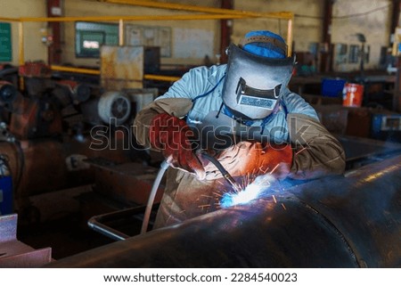 Welder is welding added joint a pipe carbon for steel structure work with process Flux Cored Arc Welding(FCAW) and dressed properly with personal protective equipment(PPE) for safety.