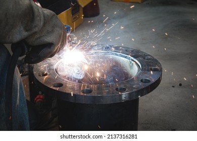 A welder is welding a flange assembly to a water pipe system.