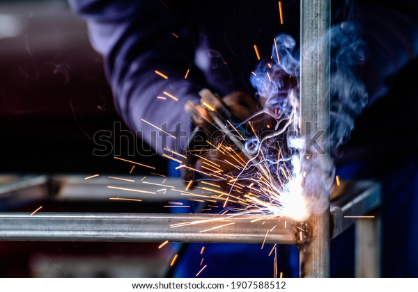 welder and welding sparks, construction and metal\
work industrial concept, metal welding with sparks, laborer or\
labor day concept