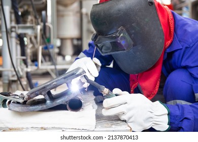 The welder is welding the Steel plate with Tungsten Inert Gas Welding process (TIG). The welder wears protective equipment with a mask and heat resistant gloves.