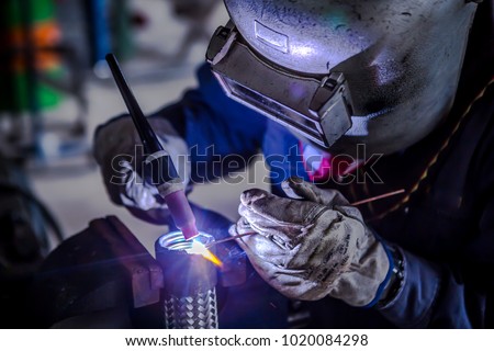 Welder is welding Tungsten Inert Gas welding, TIG weld for making new stainless flexible hose in manufacturer workshop / TIG welding torch