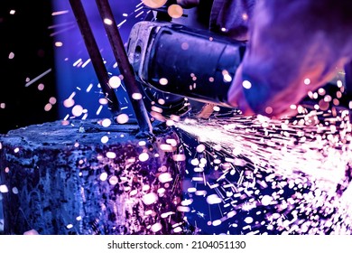 A welder welds metal into his workshop. Blue welding sparks. Gas combustion and blue smoke. Small welding workshop. Welding juncture of metal construction - Shutterstock ID 2104051130