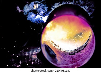 A welder welds metal into his workshop. Blue welding sparks. Gas combustion and blue smoke. Small welding workshop. Welding juncture of metal construction - Shutterstock ID 2104051157