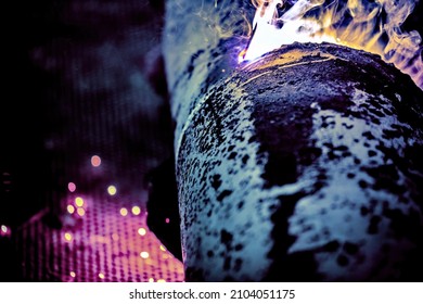 A welder welds metal into his workshop. Blue welding sparks. Gas combustion and blue smoke. Small welding workshop. Welding juncture of metal construction - Shutterstock ID 2104051175