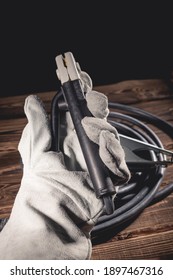 The Welder In White Welding Leather Gloves Holds A Wire With An Electrode Holder In His Hand. Studio Photo In Hard Light.