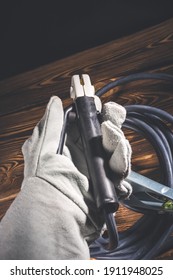 The Welder In White Welding Leather Gloves Holds A Wire With An Electrode Holder In His Hand. Studio Photo In Hard Light.