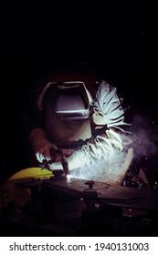 Welder At Work On A Black Background With Sparks And Welding Fumes In Full Protective Gear - Personal Protective Equipment (PPE)