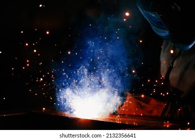 Welder at work. Welding of metal sparks and smoke in the workshop. Industrial Welder With gas Torch in Protective Helmet, welding metal profiles. The welding operation at construction site - Powered by Shutterstock