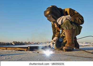 Welder Working With Electrode At Arc Werding In Construction Site Winter Outdoors